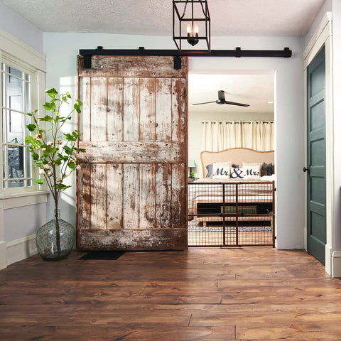 Farmhouse room with wooden floor and rustic sliding door, showcasing Position And Lock Tall And Wide Adjustable Baby Gate For Doorways 31 To 50 Inches Wide And 32 Inches Tall Easy One Hand Latch Kid Friendly Farmhouse Collection Safe Gate For Nurseries Stairs And Play Areas in nursery setting.