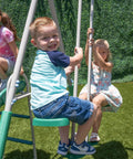 Kids playing on Outdoor Backyard Playset With 2 Swings, Glide Ride, Trapeze And 5Ft Wave Slide, enjoying the swing features.