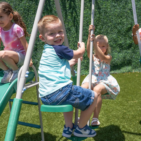 Kids playing on Outdoor Backyard Playset With 2 Swings, Glide Ride, Trapeze And 5Ft Wave Slide, enjoying the swing features.