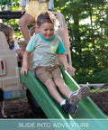 Child sliding down a green slide of Truck Climber Outdoor Playset For Kids, Backyard Playground With Slide And Climbing Wall.