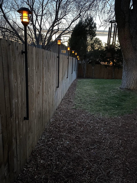 Deck or Fence Mount for Tiki Torches and 1-1/4-Inch Poles Fits Solar Lights Black Outdoor Torch Bracket in evening garden setting.