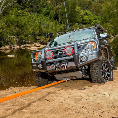 4x4 vehicle using RK12A Weekender Recovery Offroad Kit with 17500 lb snatch strap to get unstuck from sand near river.