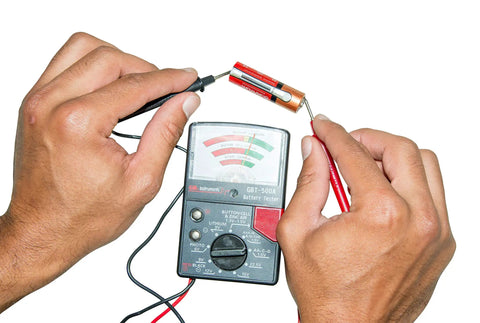 Analog Battery Tester With Test Leads For All Common Batteries From 1.5V Button Cells To 12V Lantern Batteries, AA And AAA, 9V, 14 Battery Range, Easy Read Meter, Black, in use demo image showing hands testing AA battery with meter.