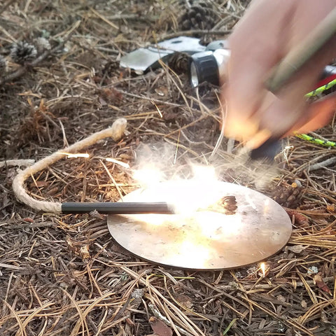 Using Ferro Rod Fire Starter Kit With A Large One Half Inch Rod, Fire Tinder And Custom Carry Pouch, All In One Survival Fire Starting Tool Package For Backcountry Camps And Emergencies In Green on forest floor.
