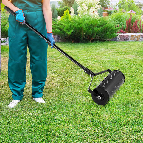 Person using Beefy Rolling Lawn Aerator With Fillable Drum And 18 Inch Tine Spikes on green grass.