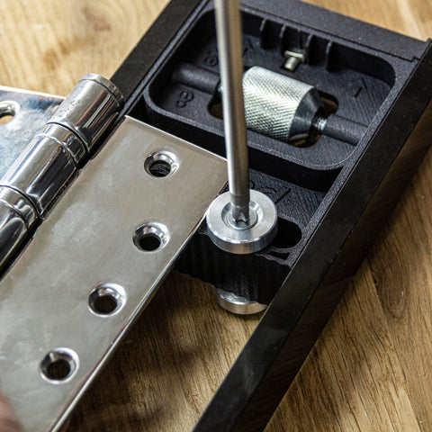 All-In-One Adjustable Door Hinge Jig Installation Kit For 2 Ft 6 In To 9 Ft Doors, No-Fuss Hands-Free Foot Operated Lifter, Sturdy Door Stand, And Pro Router Bit By Trend showing close-up of hinge placement on wooden surface.