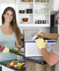 Man cutting box wearing yellow gloves for housework, woman holding bouquet in kitchen