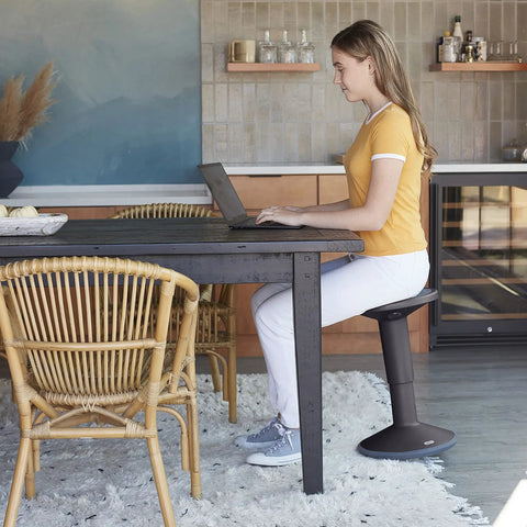 Woman using SitWell Wobble Stool With Adjustable Height For Active Seating In Seafoam, A Dynamic Classroom Stool in a home office.