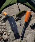 Ferro Rod Survival Kit With Flint And Steel Fire Starter And Whistle Easy Grip Emergency Fire Starter Tool displayed on rocky ground.