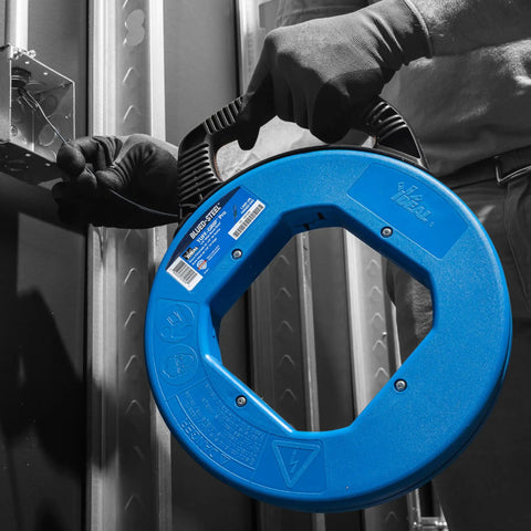 Pro Grade Blued Steel Fish Tape, 240 Feet Long, One Eighth Inch, 1600 Lb Tensile Strength, Rust Resistant, Laser Etched Measurements, Ultra Durable Tuff Grip Pro Case for Hard Wire Pulling Jobs held by worker