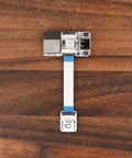 Plug And Play Smart Home Sensor Hub Delivered As A Straight Up Game Changer For Quick Home Assistant Setup With Zero Sweat Soldering Required And Dual Expansion Ports Linked To A Visual Device Builder For Smooth Local Control, showing a compact sensor module with ribbon cable on wooden surface.