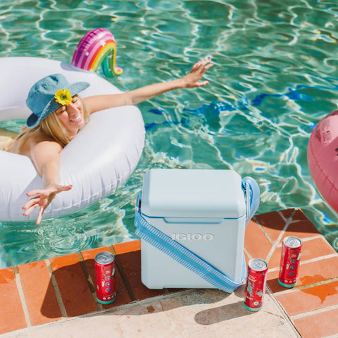 Powder Blue 11 Qt Tag-Along Two Strapped Picnic Style Cooler With Hands Free Crossbody Strap by poolside, cans nearby