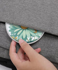 Mint Green Watercolor Daisy Wireless Charger Pad With 10W Fast Charging Portable Qi Charger Pad being placed in a bag