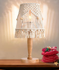 Boho Cotton Rope Bedside Lamp With Handmade Bohemian Shade, on wooden base, decorated with gifts, emitting a warm glow.