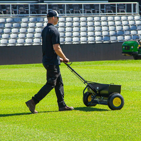 Person using Spyker P70-12010 Commercial Drop Spreader With 120 Lb Hopper, 36 Inch Spread Width, Powder Coated Steel Frame on lawn