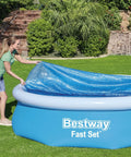 Woman placing Hella Effective 10 Foot Solar Pool Cover That Locks In Heat And Shields Against Debris on inflatable pool.