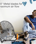 20 Inch High Velocity Wall Mount Fan With Pivoting Head next to artist with paint, showcasing its durable metal blades and easy airflow adjustment.