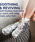 Person using Cozy Self-Heating Tired And Achy Feet Soothing Foot Mask With Warming Booties Moisturizing Socks Infused With Epsom Salt