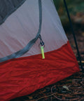 Ni Glo 2-Inch UV Rechargeable Glow Keychain For Camping Scuba Diving Night Fishing Hiking Emergency Kits And Everyday Carry attached to tent