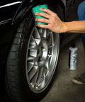 Hand using Wonder Wave Durafoam Tire Shine Applicator Pads With Contour Wave Design for precise tire dressing application on car