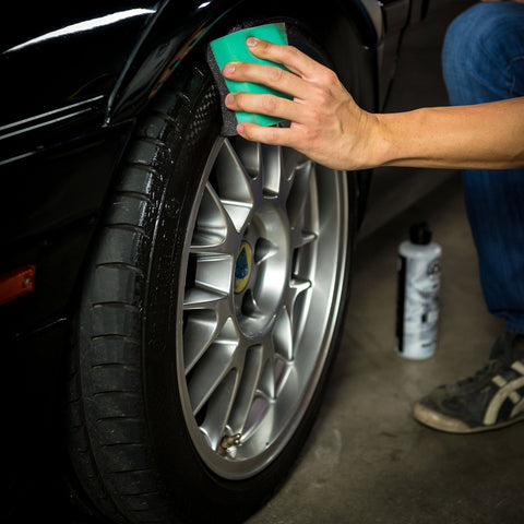 Hand using Wonder Wave Durafoam Tire Shine Applicator Pads With Contour Wave Design for precise tire dressing application on car