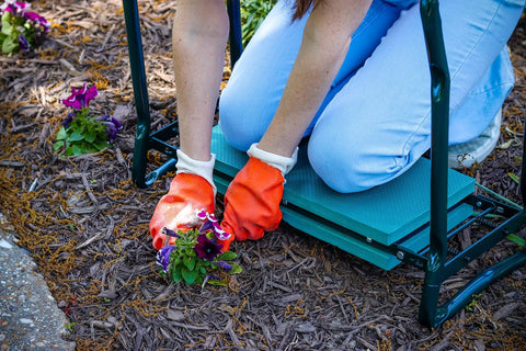 A person using a Garden Kneeler And Wide Seat That Flips Into A Comfy Sit Down Stool for pain-free weeding and planting on the go.