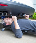 Pro Lift C-9100 Black 40 Inch Foldable Hydraulic Repair Creeper With Padded Seat And Headers in use under a vehicle.