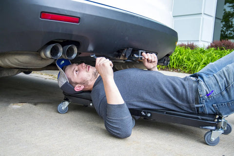 Pro Lift C-9100 Black 40 Inch Foldable Hydraulic Repair Creeper With Padded Seat And Headers in use under a vehicle.