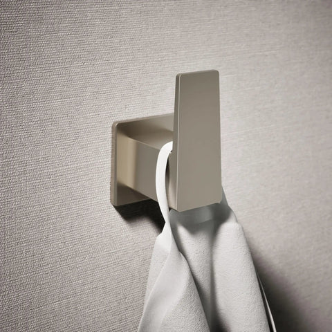 Honesty Robe Hook in Brushed Nickel for bathroom, holding a towel, mounted on textured wall, modern design with clean lines.