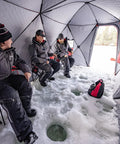 Three people using Quickfish Six Person Portable Pop Up Ice Fishing Shelter With Fully Quilted Insulation No Trip Door And Deluxe Anchors For Hell Of A Winter Setup In Red Black.