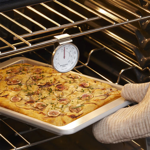 Dial Oven Thermometer With Rotating Clip And Stand For Precise 100F To 600F Temperature Readings In Your Oven beside baking dish.