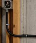 Built Tough Workhorse Corrugated Flexible Conduit Pipe With Compression Fitting Connector For Electrical Cable Routing And Wiring Harness Protection Rated At 20 Bar Pressure In A Sturdy 19 Millimeter Coil mounted on wooden wall.