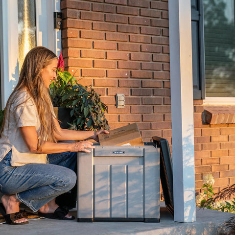 Woman opening package from the Versatile Outdoor Storage Cube Deck Box, a 25-gallon patio organizer.