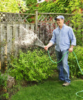 Person watering garden with green hose, showcasing irrigation use. Note: Clear Silicone Tubing visible in another context.