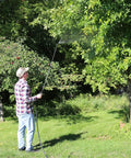 Person using Farm Grade Adjustable Spray Gun With 50 Inch Reach, 18 Orifice, 150 Psi Max, spraying tree branches in garden