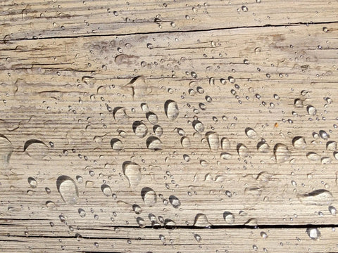 Water droplets on wood surface showcasing Heavy Hitter Water Repellent Concrete Sealer Boasting A Natural Matte Finish Water Based Low Voc Formula For Driveways And Patios Drops Ultimate Storm Shield Protection Without Gunky Shiny Buildup Inside A Chunky Five Gallon Container.