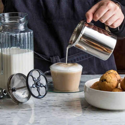 Handheld Milk Frother For Creamy Foam In Seconds, On The Go Stainless Steel Foamer in use with cup of coffee on table