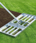 Lawn Leveling Rake 30 Inch By 10 Inch Heavy Duty Carbon Steel Ground Leveler Tool smoothing grass and soil in a garden.