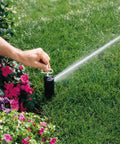 Person adjusting PGP Adjustable Rotor Sprinkler Nozzle 10 Pack Red With Installation Key Included For Lawn Care And Irrigation on lawn