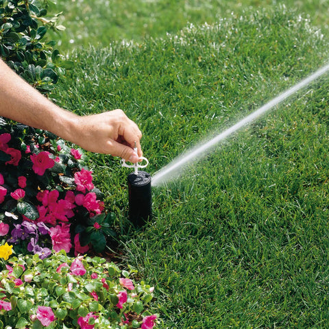 Person adjusting PGP Adjustable Rotor Sprinkler Nozzle 10 Pack Red With Installation Key Included For Lawn Care And Irrigation on lawn