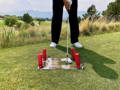Golfer using Speed Trap Two Point Zero Golf Swing Trainer on green field with polycarbonate base and red rods visible