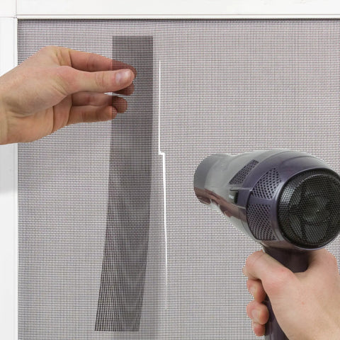 Applying Window Screen Repair Kit 2 Inch By 80 Inch Roll Charcoal using hair dryer for DIY fixes on window screen tear.