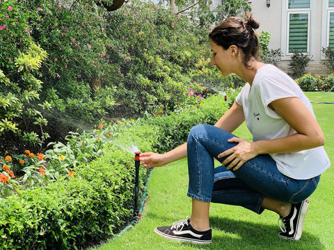Person adjusting Multi-Adjustable Flex Design Garden Sprinkler With Extension Set For DIY Gardeners on lawn bed