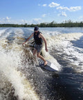 Person surfing on Mondo 5 Foot 2 Inch Wakesurf Board with EVA Padding Thruster Fin Design on a lake wave