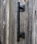 Side view of 12 Inch Rustic Black Barn Door Handle Pull for DIY Sliding Barn Door Hardware Kit installed on a wooden door.