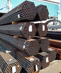 Stacked industrial metal pipes outside a warehouse