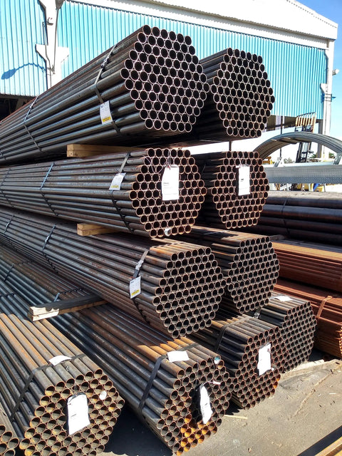 Stacked industrial metal pipes outside a warehouse