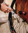 Person using Tubeless Sealant Injector Syringe And Presta Valve Core Removal Tool For Stans No Tubes on a bike tire