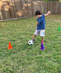 Child playing soccer among 9 Inch Heavy Duty Agility Training Cones for Soccer Football Basketball and Sports Drills Set of 12 in Bright Orange High Visibility Durable PVC Built for Rugged Outdoor and Indoor Practice and Drills Drill Ready Gear on grass field