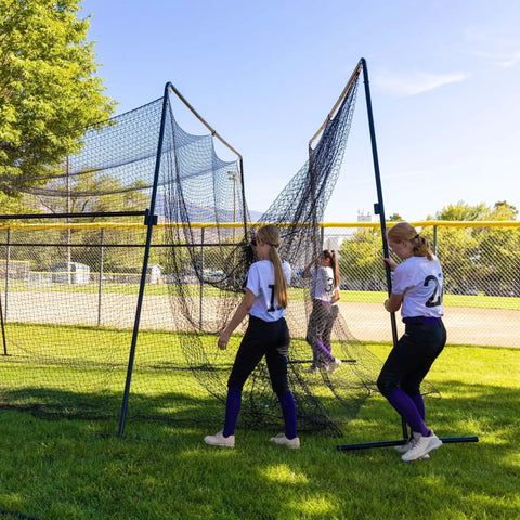 Children assembling a 40 Foot Collapsible Batting Cage For Backyard Or Indoor Baseball And Softball Practice With A Heavy Duty Rust Resistant Steel Frame And UV Protected Net Black Frame Easy Setup Durable Year Round Hittin Cage on a grassy field.